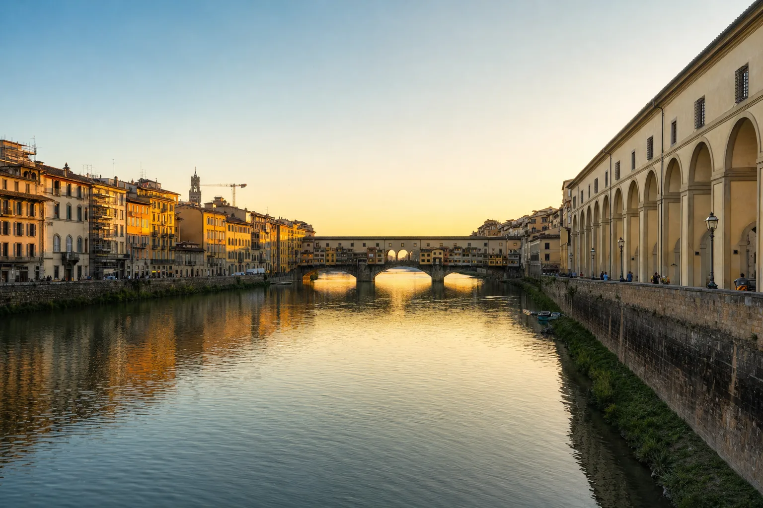 AI-generated image: Arno River, Florence: A serene view of the Arno River at sunset, with the iconic Ponte Vecchio gracefully arching over the water. Elegant palazzi line the riverbanks, their reflect